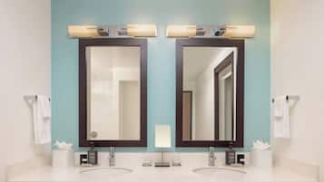 Un baño con dos lavamanos, un espejo y un perchero para toallas.