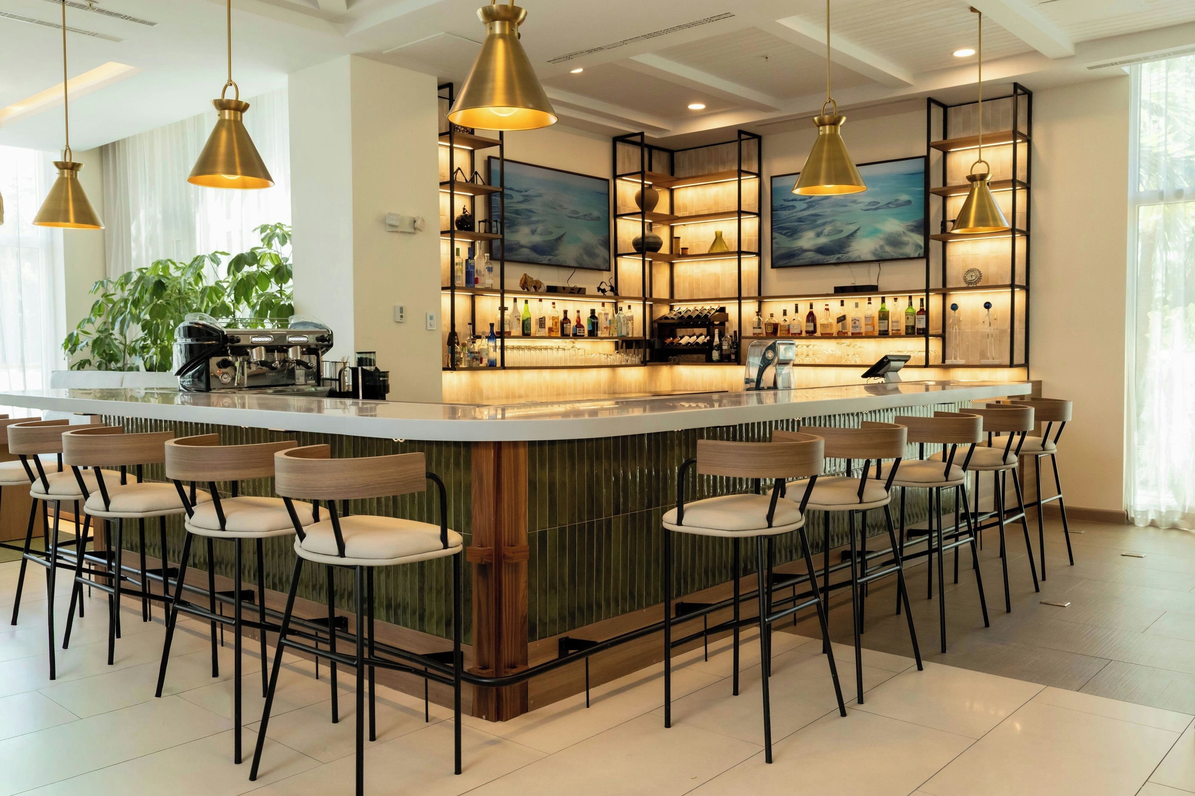 Een bar met een centraal eiland, verschillende zitmogelijkheden en hangende verlichtingsarmaturen.