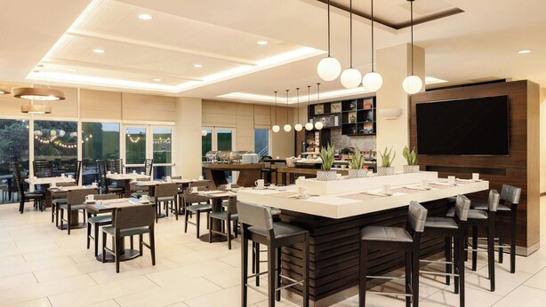 Un'area pranzo moderna con isola centrale, sgabelli da bar e illuminazione a sospensione.