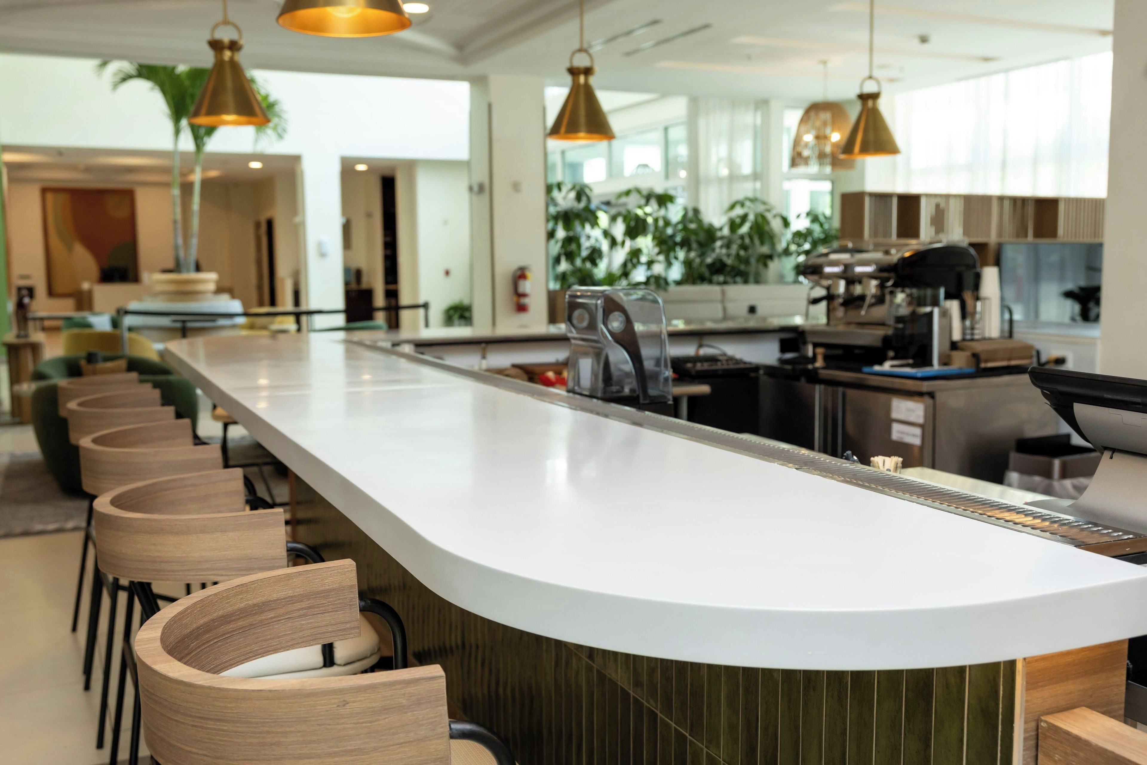 A modern kitchen with a long counter, bar stools, and pendant lighting.