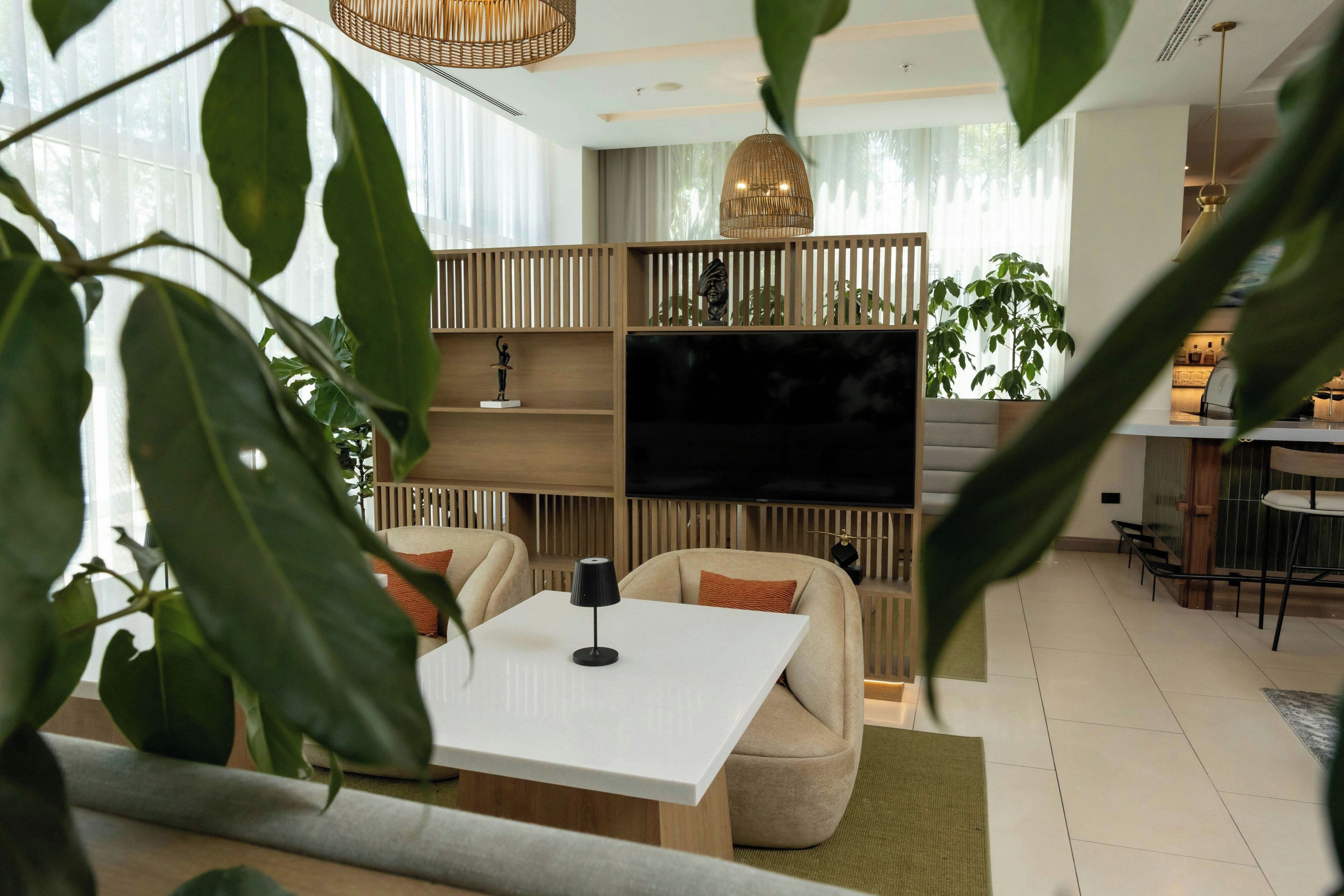 A modern living room with a flat-screen TV, a dining area, and a kitchen in the background.