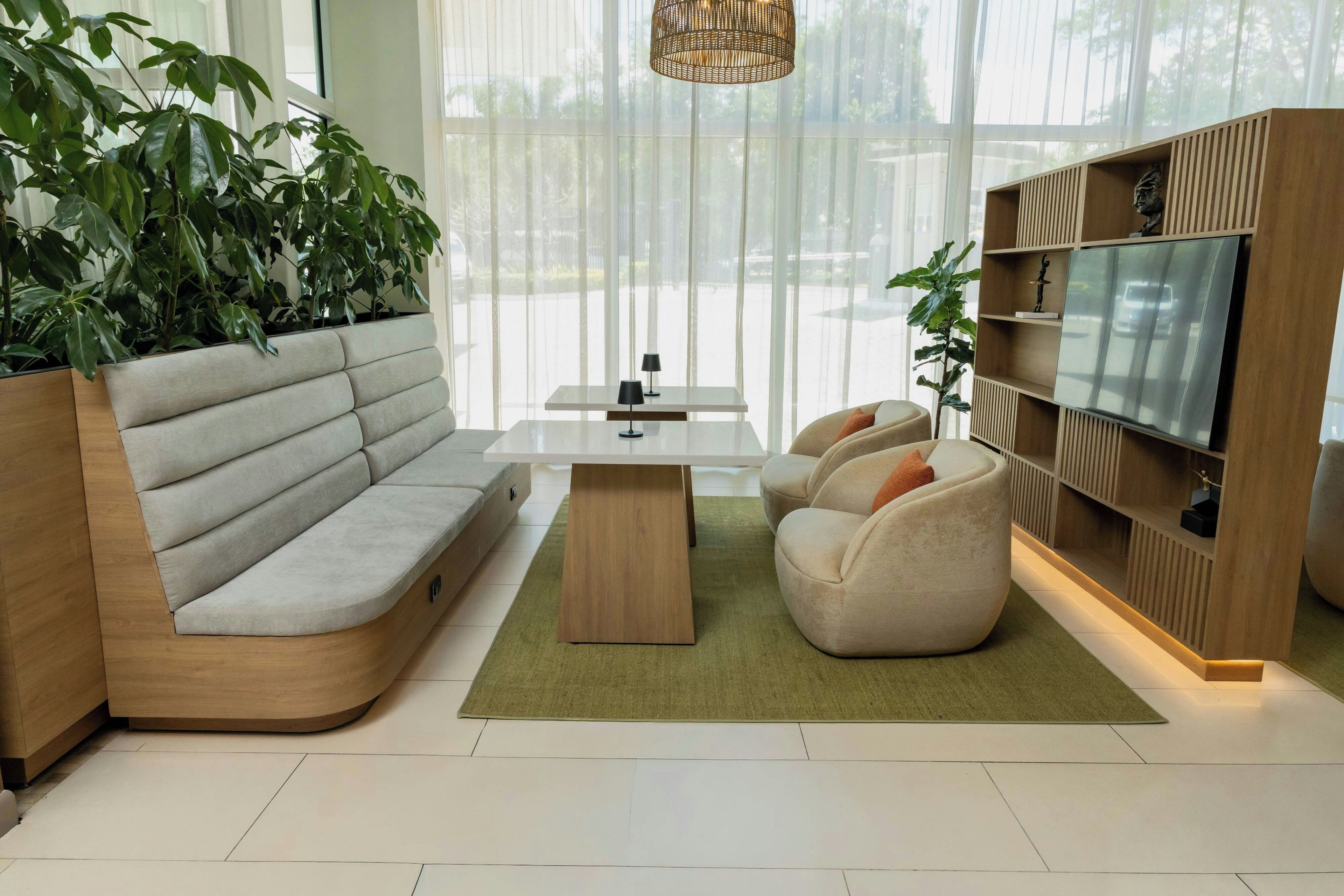 A modern living room with a sectional sofa, a coffee table, two armchairs, a TV, and a bookshelf.