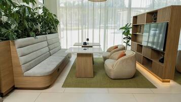Uma sala de estar moderna com um sofá seccional, uma mesa de centro, duas poltronas, uma televisão e uma estante de livros.