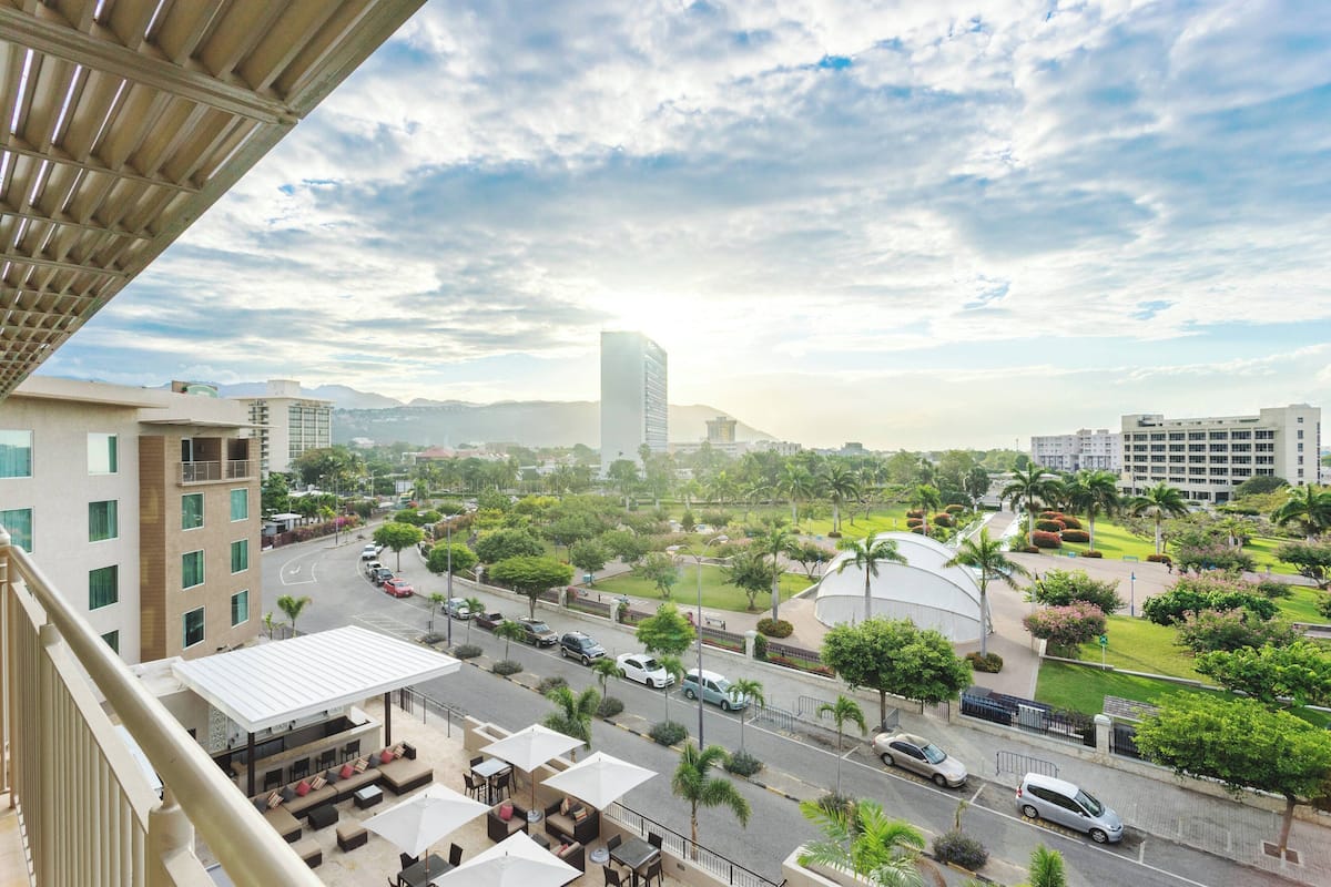 A hotel with outdoor seating and a view of a cityscape.