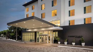 Ingresso moderno di un hotel con una tettoia, porte in vetro e piante in vaso.