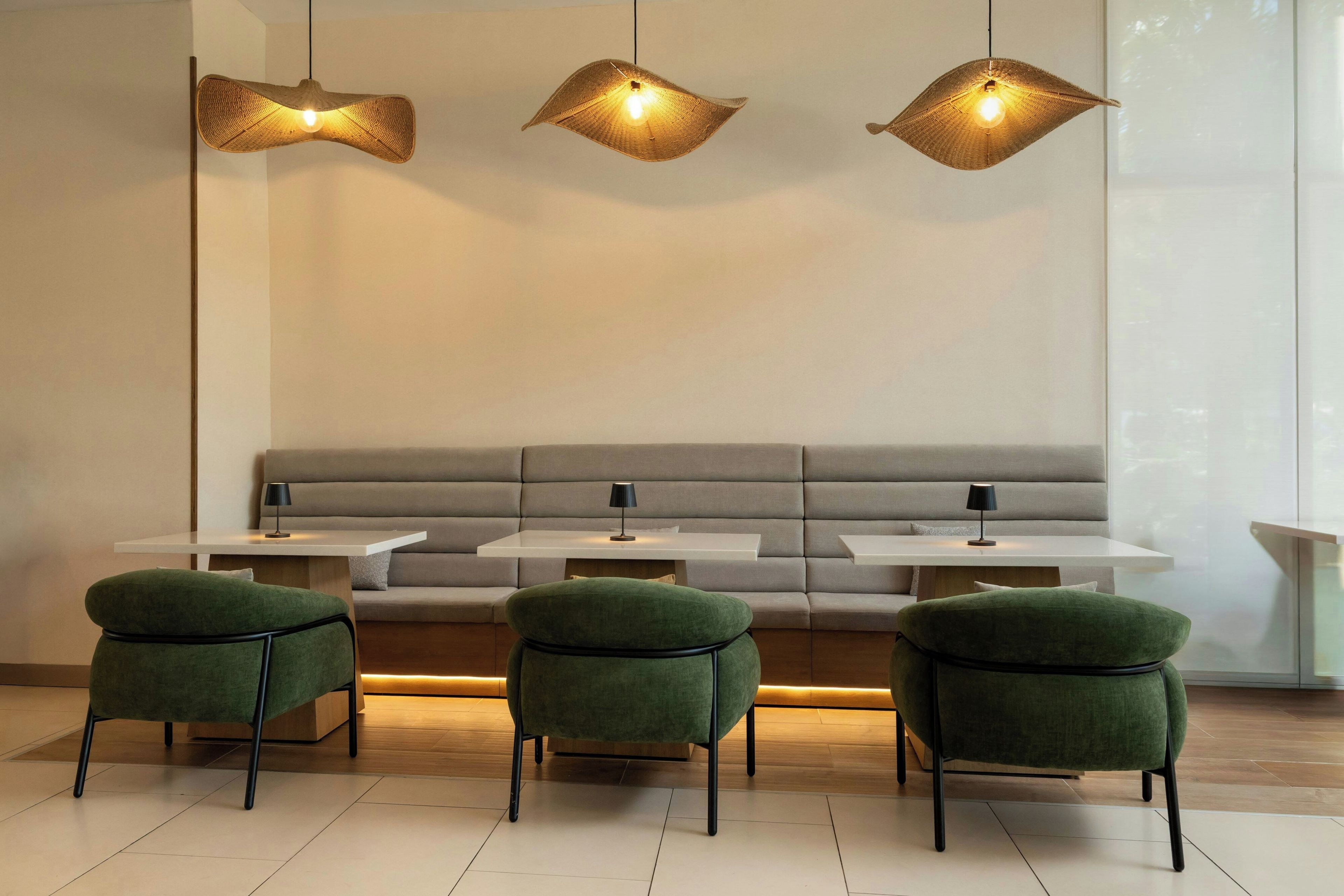 Un espacio moderno con zona de estar, sofá y tres sillones, una mesa y tres lámparas colgantes.