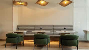 Een moderne zithoek met een bank, drie stoelen, een tafel en drie hanglampen.