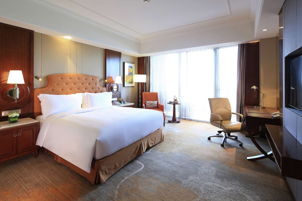 Una habitación de hotel con una cama grande, un escritorio, una silla y un televisor.
