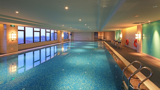 Una piscina interior con ventanales, un flotador salvavidas y una escalera.