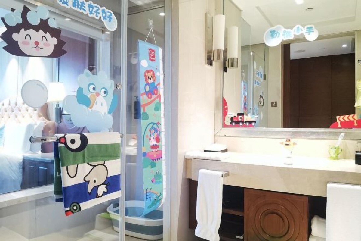 A bathroom with a children's play area, a large mirror, and a toilet with a circular design.