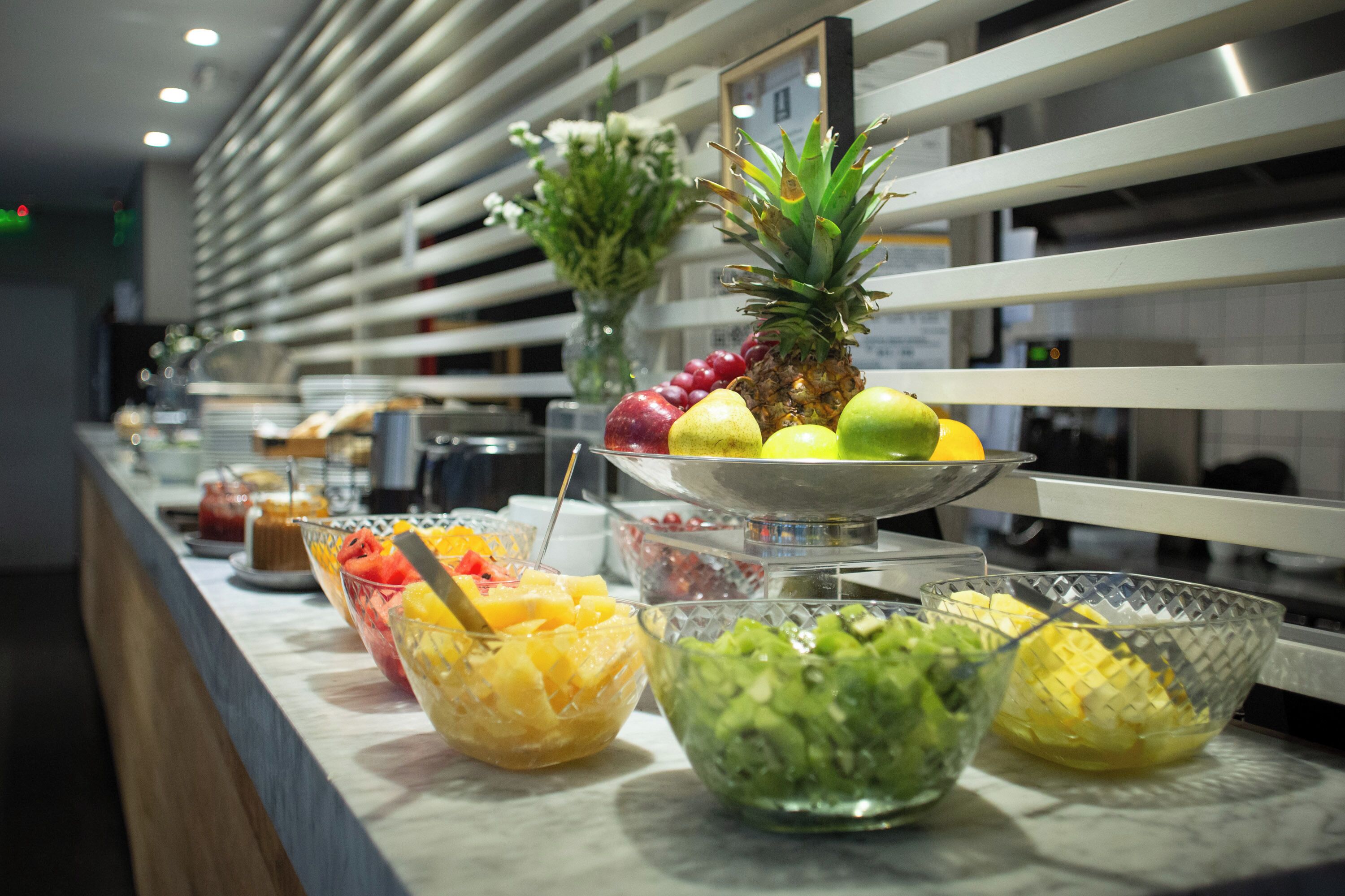 A buffet with various fruit bowls and a pineapple centerpiece.