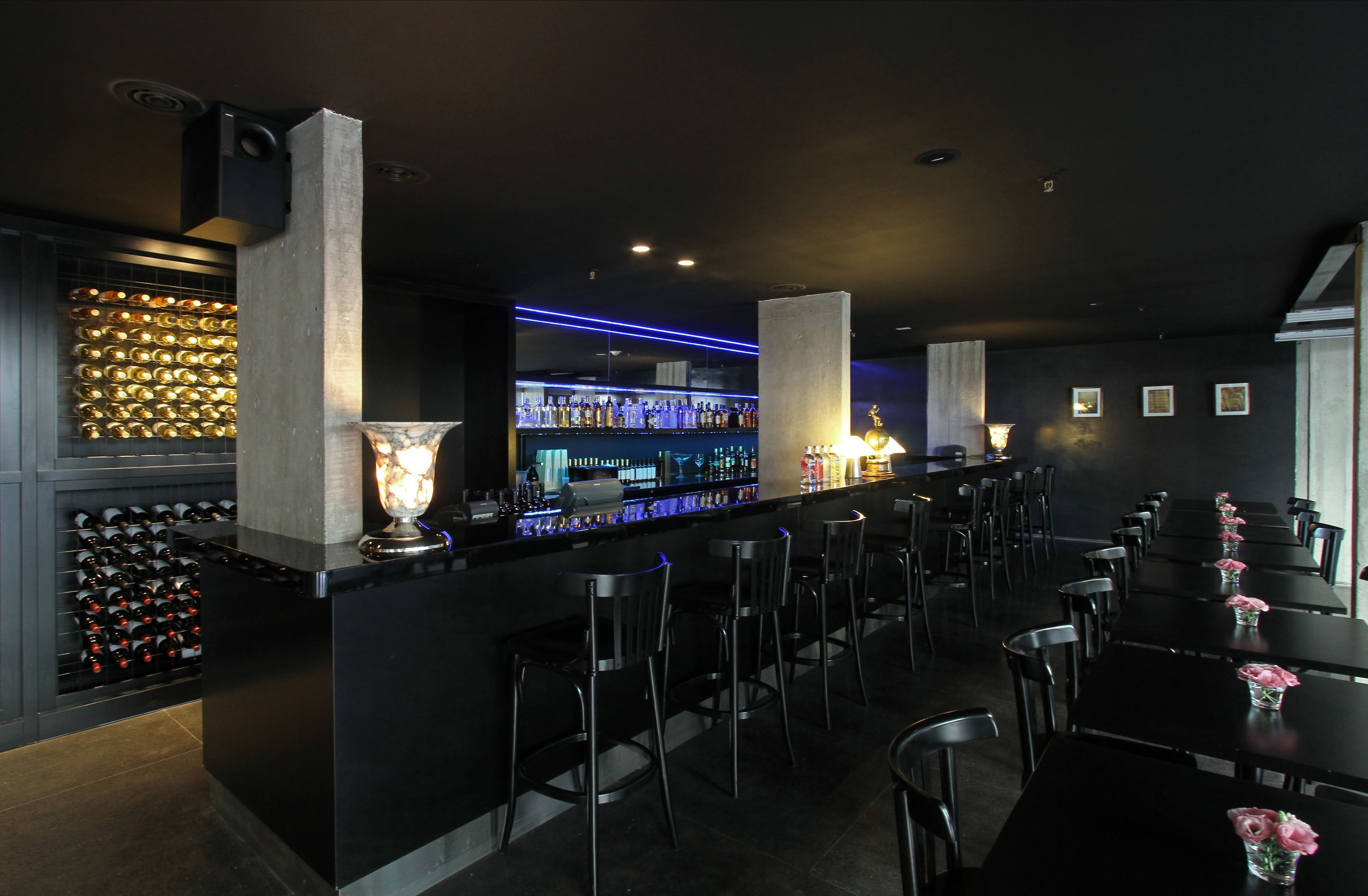 Zona de bar con estantería para vinos, barra y asientos.