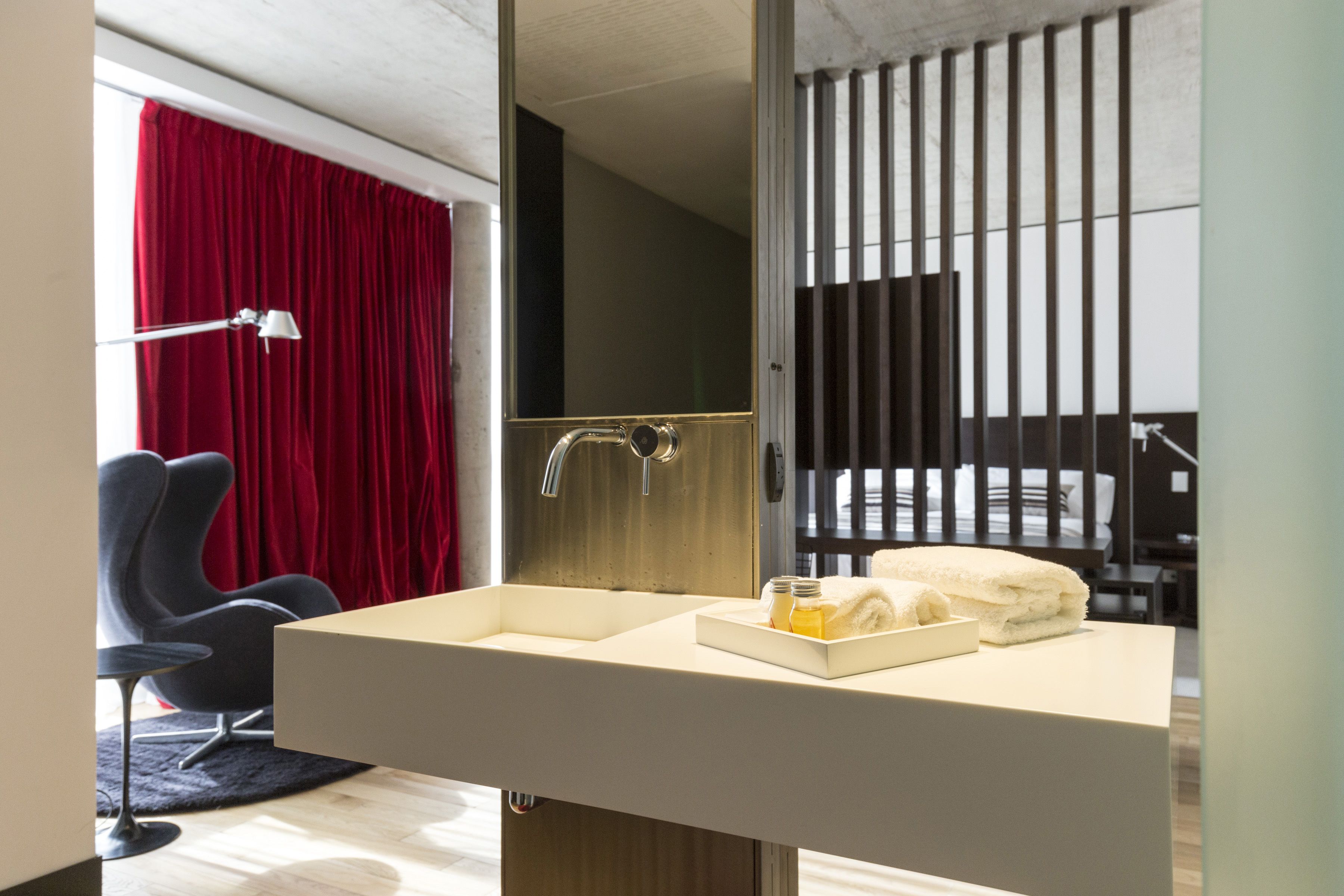 A modern bathroom with a large sink, a mirror, and a red curtain.