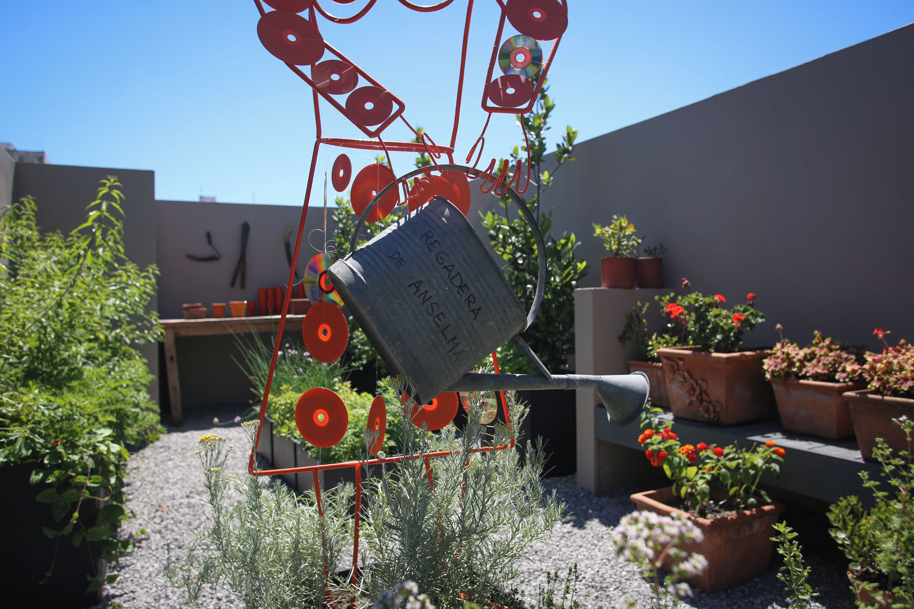 A garden with potted plants and a metal sculpture.