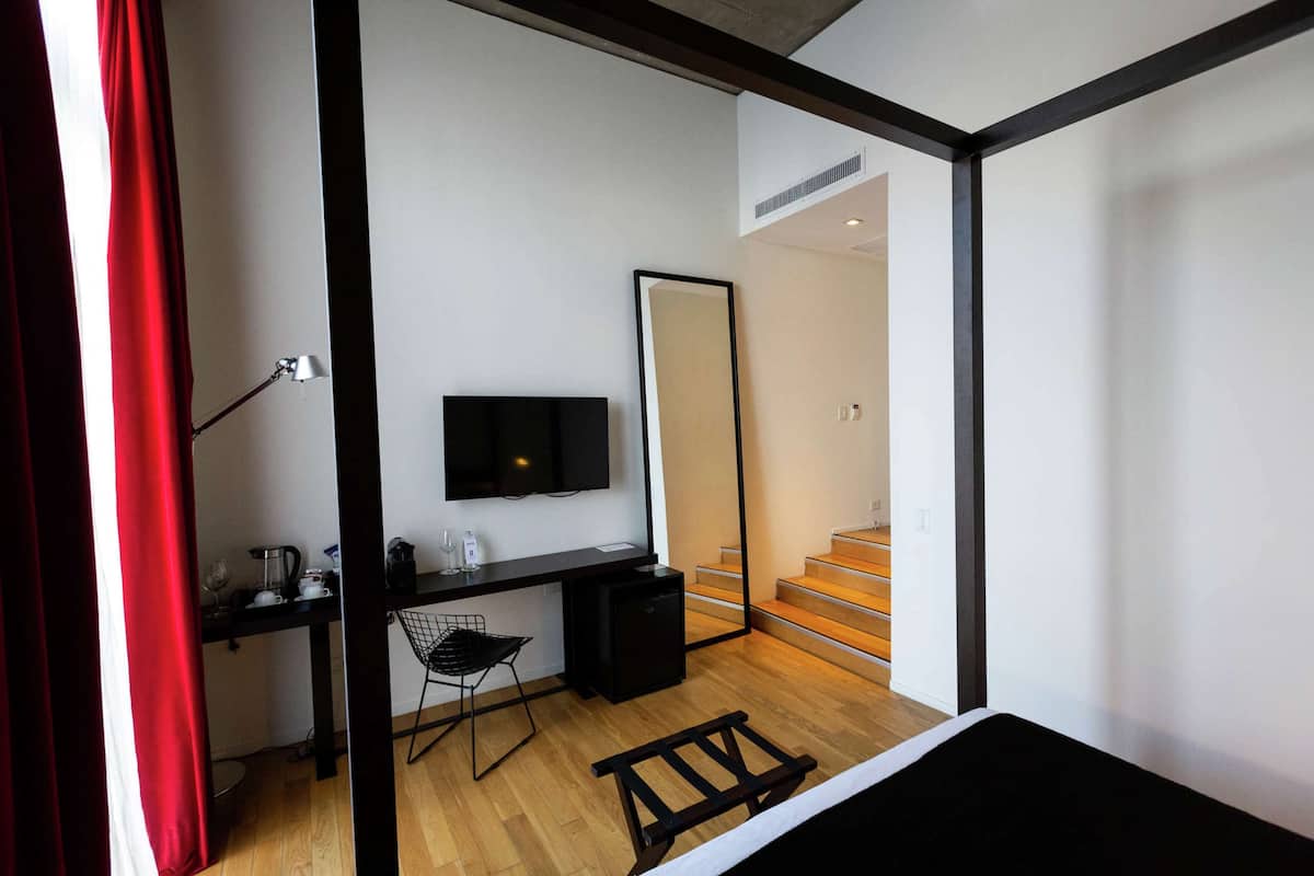 A modern bedroom with a desk, chair, and a TV mounted on the wall.