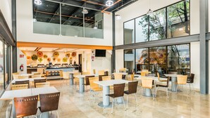 Un amplio comedor interior con varias mesas y sillas, un mostrador con productos alimenticios y ventanas grandes que dejan entrar luz natural.