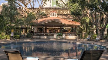 Una piscina al aire libre, sombrillas, sillones reclinables de piscina
