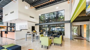 Un vestíbulo amplio con una recepción, zonas de estar y grandes ventanales que ofrecen vistas al exterior.