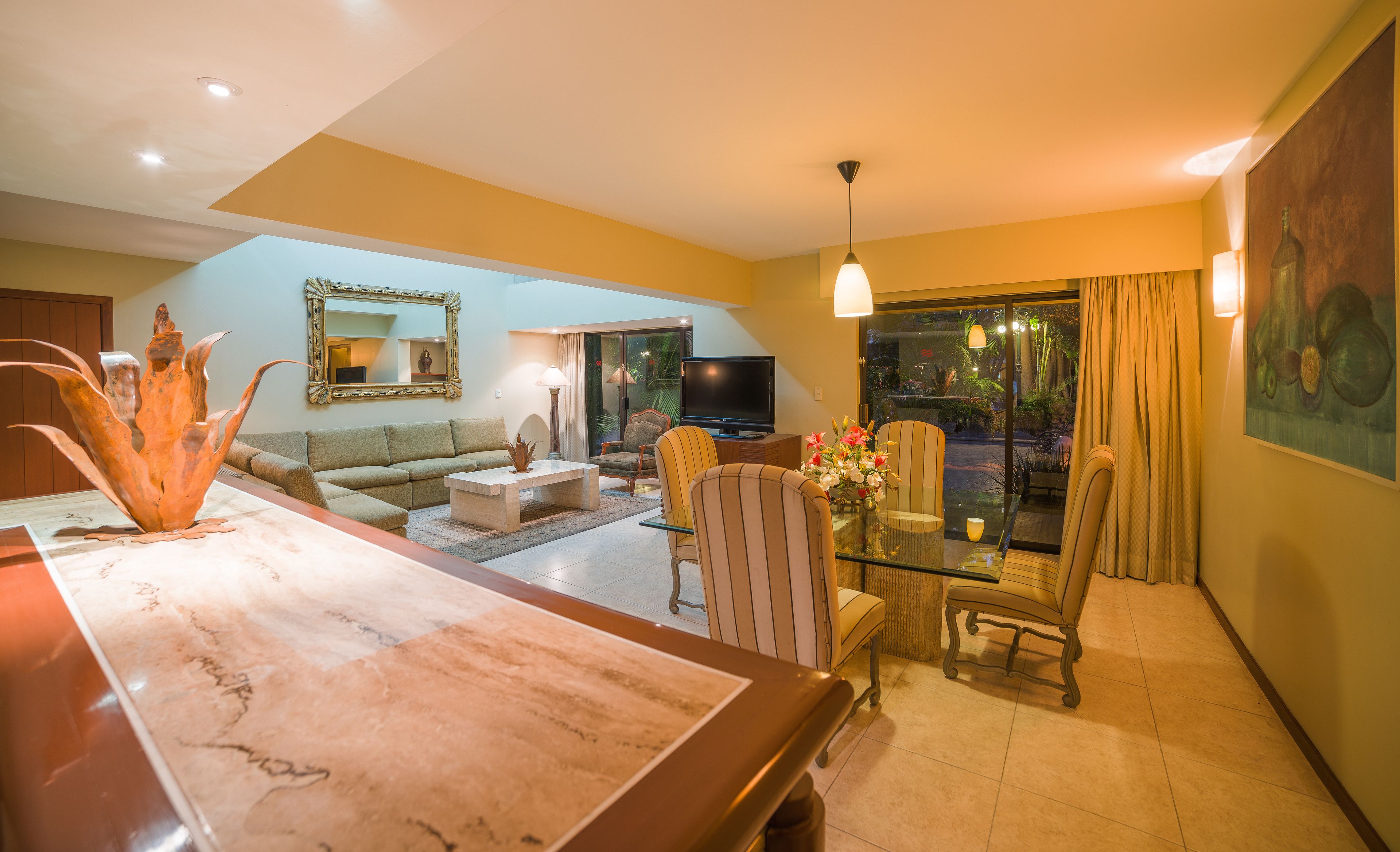A living room with a sofa, coffee table, TV, and a dining area with chairs.
