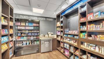 A snack and beverage section with shelves stocked with various snacks and drinks, a refrigerated display, and a 'Welcome to Kenosha' sign.