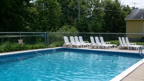A rectangular swimming pool with clear blue water, surrounded by a metal fence. - Sunnyside Motel & Cottages (Bar Harbor)