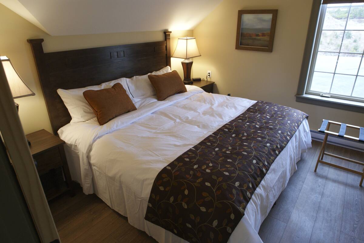 A neatly made bed with a patterned bedspread, a wooden headboard, and bedside lamps.
