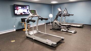 A fitness room with treadmills, a TV, and exercise equipment.