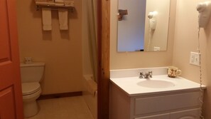 Un baño con inodoro, lavamanos, secador de pelo y espejo.