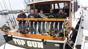 Un barco llamado 'Top Gun' atracado en un puerto deportivo, con varios peces exhibidos en la cubierta.