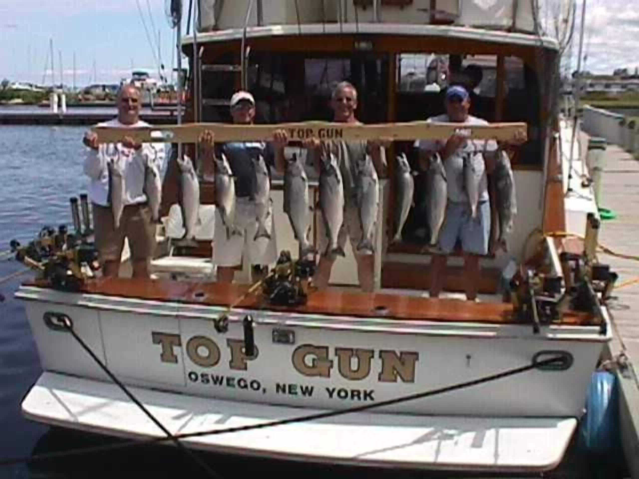 A boat named 'Top Gun' docked at Oswego, New York, with several fish displayed on the deck.