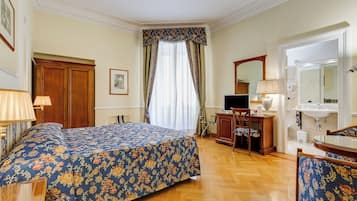 A hotel room with a bed, a desk, a chair, a television, a mirror, and a bathroom.