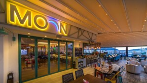 A restaurant with a 'MOON' sign, indoor seating, and a view of the sea. - Honeymoon Hotel (Marmaris)