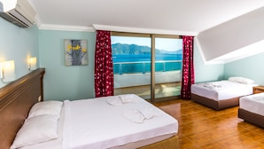 A hotel room with two beds, a balcony with a view of the sea, and a painting on the wall. - Honeymoon Hotel (Marmaris)