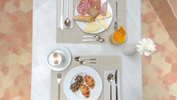 Una mesa de desayuno con platos de comida, cubiertos y una flor.