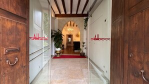 Entrada de un hotel con alfombra roja, puertas de madera y un candelabro.