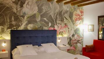 Habitación de hotel con una cama grande, un sofá rojo y un mural floral en la pared.