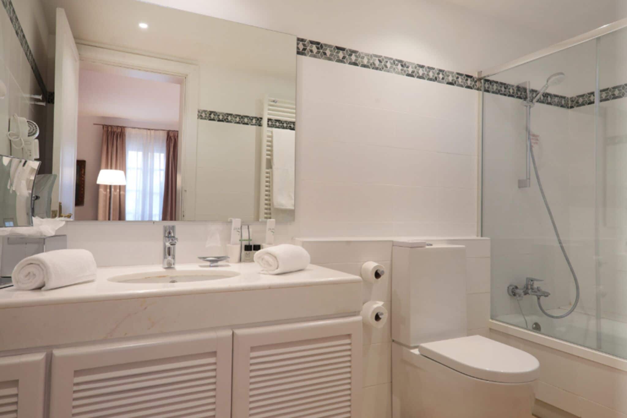 A modern bathroom with a glass-enclosed shower, a white sink with a mirror, and a toilet.