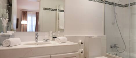 A modern bathroom with a glass-enclosed shower, a white sink with a mirror, and a toilet.