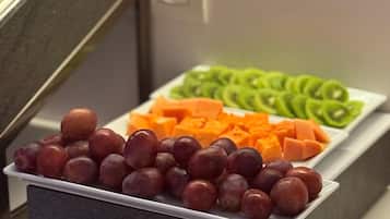 Un bufé con frutas y verduras variadas, como uvas, kiwi y zanahorias.