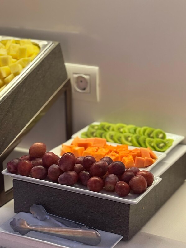A buffet with various fruits and vegetables, including grapes, kiwi, and carrots.