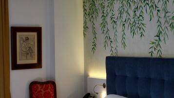 A hotel room with a bed, a chair, a nightstand, and a wall with a bamboo leaf pattern.