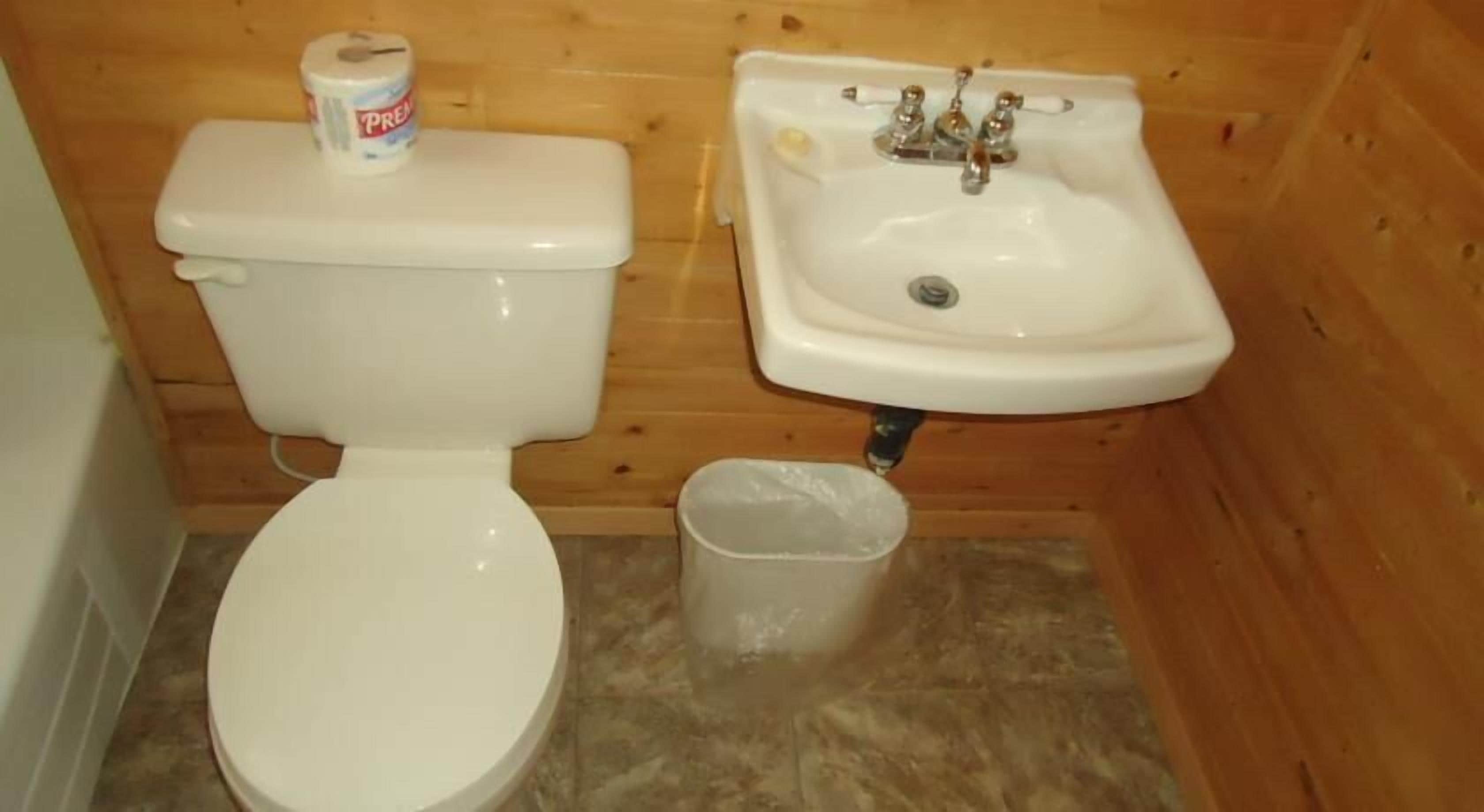 Un baño pequeño con inodoro, lavamanos y cubo de basura.
