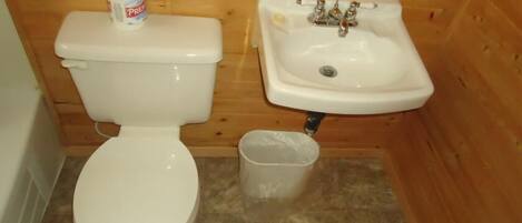 Un baño pequeño con inodoro, lavamanos y cubo de basura.