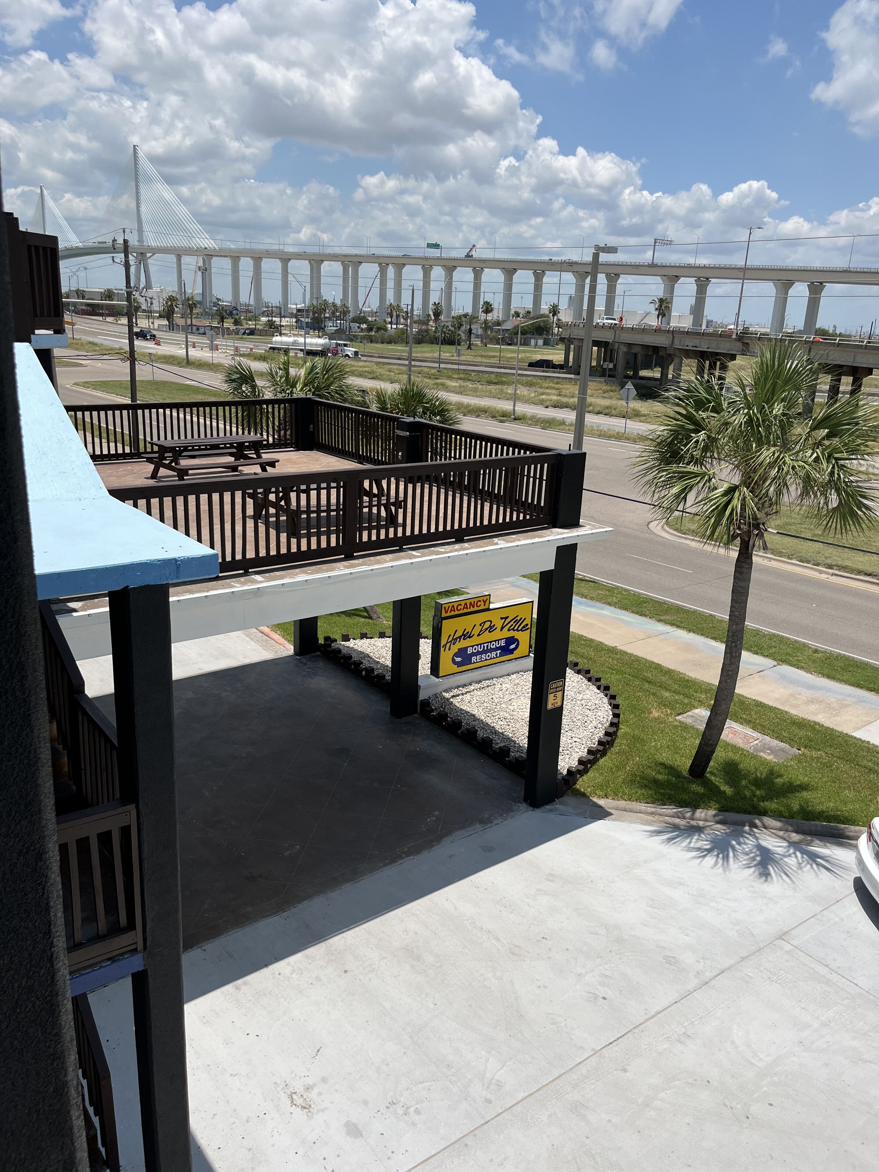 A hotel with a balcony overlooking a road and a bridge.