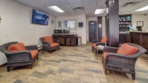 A lobby with wicker furniture, a reception desk, and a television. - Hotel De Ville (Corpus Christi)