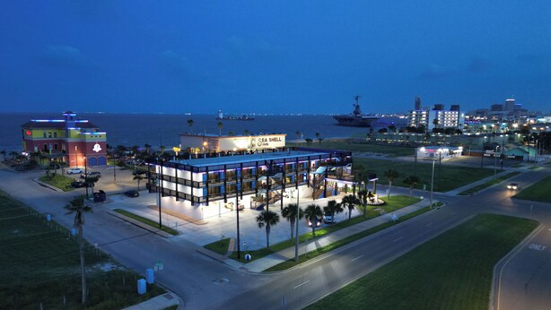 A multi-story hotel with a pool area and a view of the ocean. - Hotel De Ville (Corpus Christi)