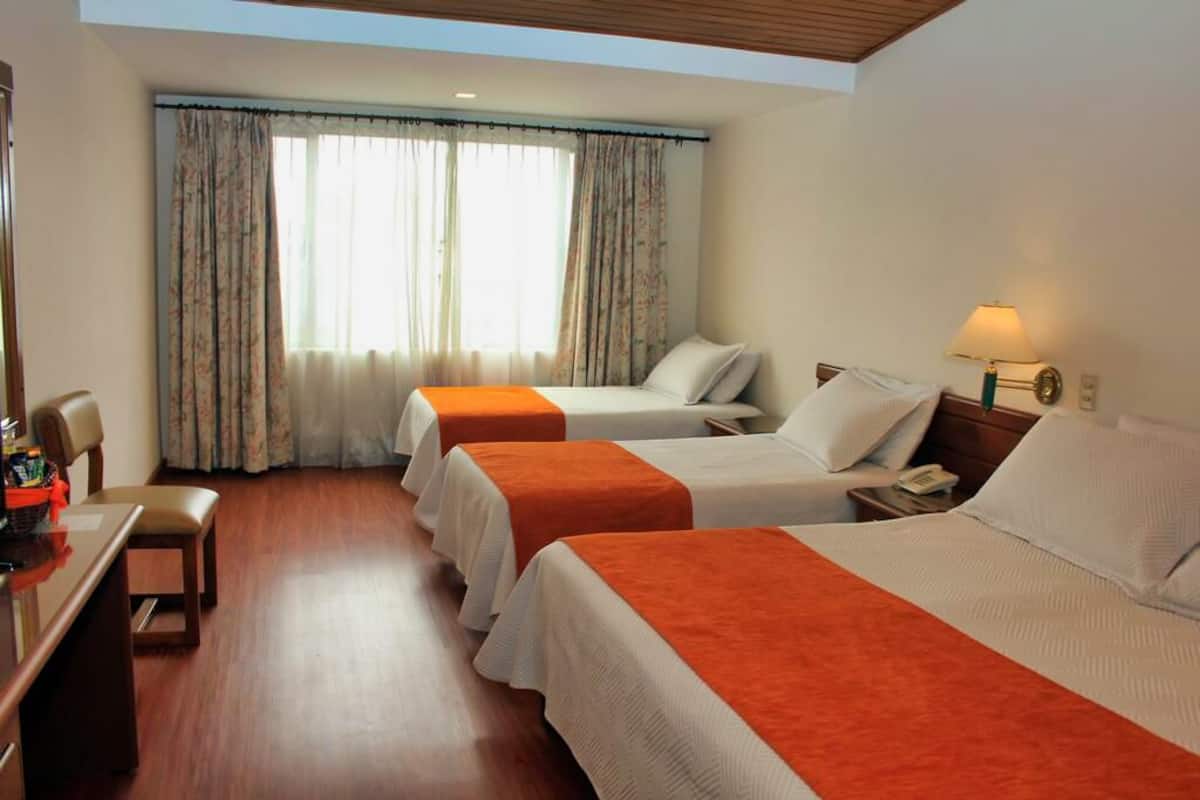 A hotel room with two beds, a desk, and a chair.