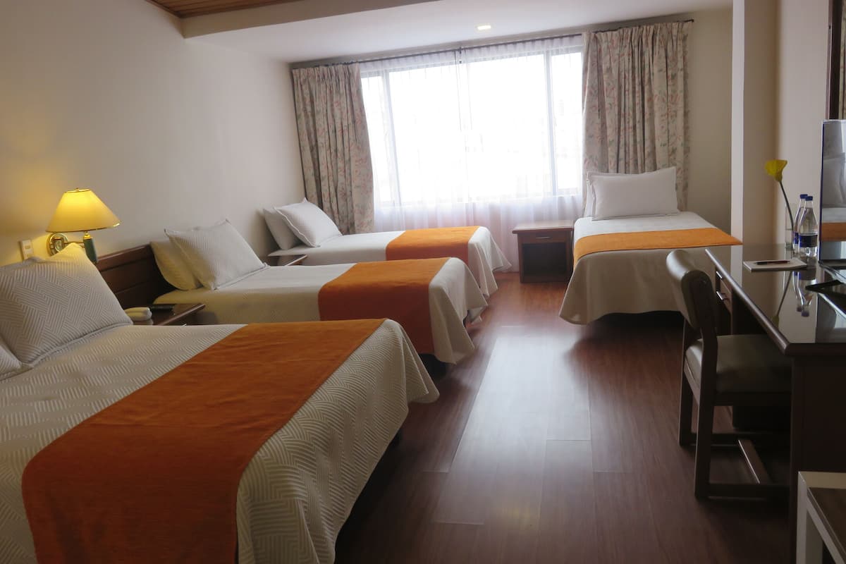 A hotel room with two beds, a desk, and a chair.
