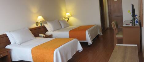 A hotel room with two beds, a desk, and a chair.