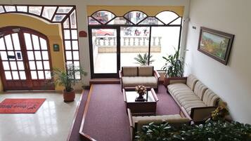 Un hall con una recepción, un sofá, una mesa de centro y plantas en macetas.